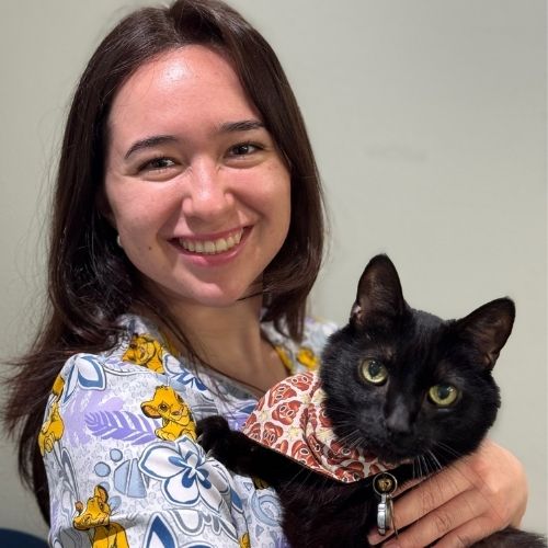 Giselle smiling and holding a black cat