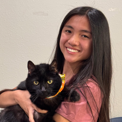 Giselle smiling and holding a black cat
