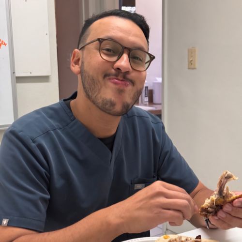 A man wearing glasses enjoys a slice of pizza